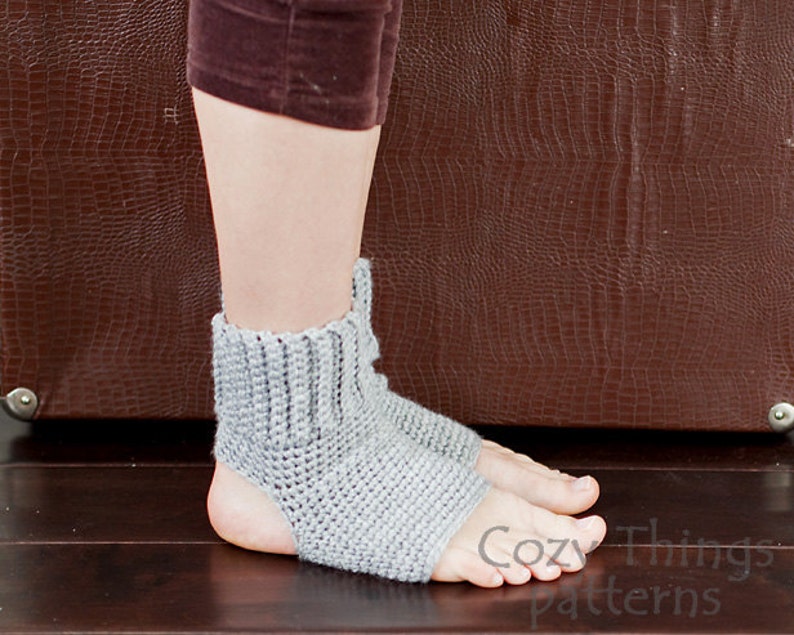 May include: Gray crocheted foot warmers with an open heel and toe. The foot warmers are shown on a person's feet.