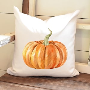 May include: A white cushion with a watercolour illustration of an orange pumpkin with a green stem.