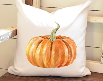 May include: A white pillow with a watercolor illustration of an orange pumpkin with a green stem.
