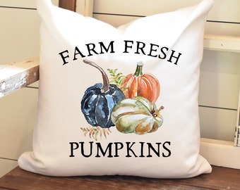 May include: White pillow with the text "FARM FRESH PUMPKINS" in black. The pillow features a watercolor illustration of three pumpkins: one orange, one blue, and one green.
