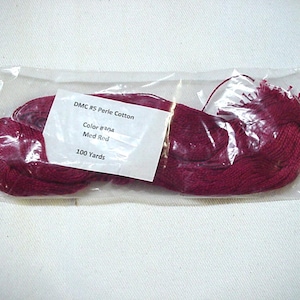 May include: A package of DMC #5 Perle Cotton embroidery floss in the color 310, a medium red. The package contains 100 yards of floss.