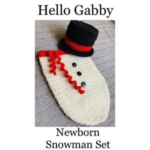 Op de afbeelding: Een pasgeboren sneeuwman set, bestaande uit een gehaakt wit lichaam met rode accenten en zwarte knopen. Inclusief een zwarte hoge hoed met een rode band. De tekst "Hello Gabby" en "Newborn Snowman Set" worden weergegeven.