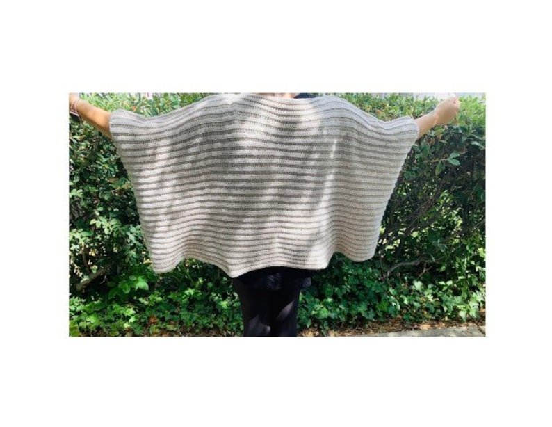 K&ouml;nnte beinhalten: Ein beigefarbener und grau gestreifter Poncho mit weiten &Auml;rmeln. Das offene Kleidungsst&uuml;ck besteht aus einem leichten, gestrickten Material. Der Poncho wird mit ausgestreckten Armen pr&auml;sentiert, um das Design und den Fall des Stoffes zu zeigen.