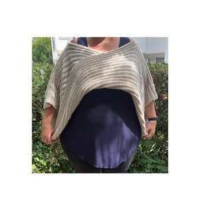 K&ouml;nnte beinhalten: Ein beigefarbener, &uuml;bergro&szlig;er Strickpullover mit V-Ausschnitt. Der Pullover hat eine gerippte Textur und kurze &Auml;rmel. Er wird &uuml;ber einem dunkelblauen Oberteil getragen. Der Stil ist l&auml;ssig und bequem.