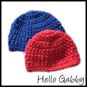May include: Two crocheted hats, one red and one blue. The hats are made with a simple stitch pattern and have a rounded crown.