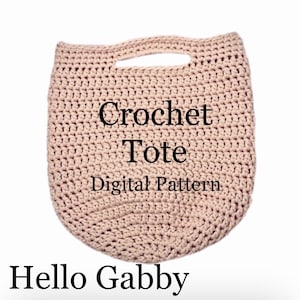 May include: A beige crochet tote bag with a handle. The text "Crochet Tote Digital Pattern" is displayed on the bag. The words "Hello Gabby" are at the bottom of the image.