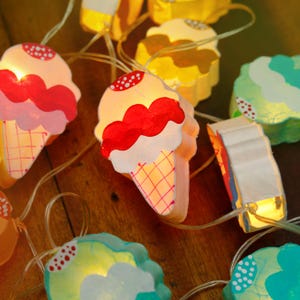 May include: String of lights shaped like ice cream cones in various colors, including pink, yellow, blue, and green. The lights are strung together with clear wire and have small LED bulbs inside.