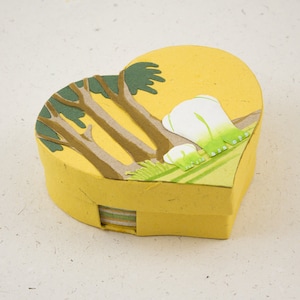 May include: A yellow heart-shaped box with a paper mache design of trees and flowers. The box is made of recycled paper and is perfect for storing small items.
