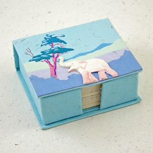 May include: A blue paper notepad with a white elephant and a blue tree design. The notepad is made of recycled paper and has a stack of blank pages inside.