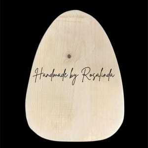 May include: A light-colored, egg-shaped wooden plaque with a smooth, natural grain finish. The text 'Handmade by Rosalinda' is printed in a black, cursive script across the center of the wooden surface, which features a small, visible knot.