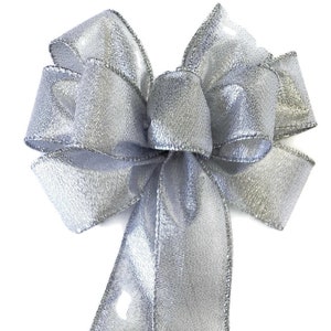 Könnte beinhalten: Eine silberne Glitzer Schleife mit zwei langen Schleifenenden. Die Schleife ist mit einem Draht gebunden.