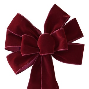 May include: A large, burgundy velvet bow with two long tails. The bow is tied in a classic, symmetrical style.