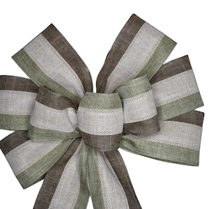 May include: A large, brown, beige, and green striped bow made of burlap ribbon. The bow is tied in a classic shape with the tails hanging down.