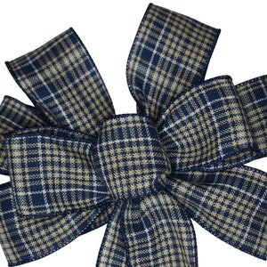 May include: A large plaid bow made from navy blue and tan ribbon. The bow is tied with a simple knot in the centre.
