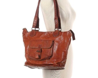 May include: A brown leather tote bag with a zipper closure and a large front pocket. The bag has a top handle and a shoulder strap.