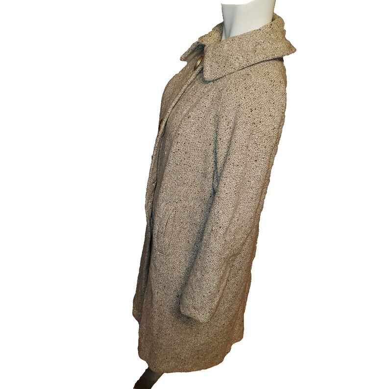 May include: A long-sleeved, beige tweed coat with a collar and a button closure.