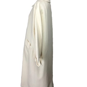 May include: A long, off-white coat with a collar and long sleeves. The coat is made of a soft, textured fabric.