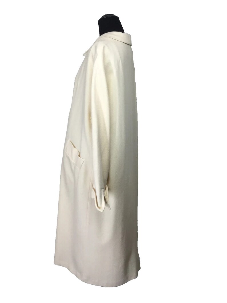 May include: A long, off-white coat with a collar and long sleeves. The coat is made of a soft, textured fabric.