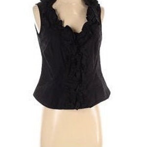 Peut inclure: Un haut noir sans manches avec un décolleté à volants et un corsage ajusté.