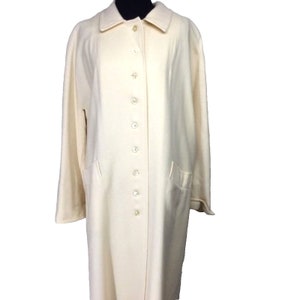 May include: A long, off-white coat with a button-up front and two pockets. The coat has a classic, simple design.