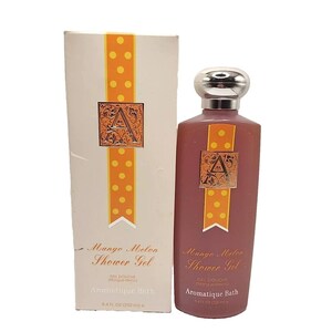 Könnte beinhalten: Aromatique Bath Mango Melon Duschgel. Das Produkt befindet sich in einer mauvefarbenen Flasche mit silbernem Verschluss und einer passenden Schachtel. Die Schachtel und die Flasche haben ein dekoratives orangefarbenes Band mit weißen Punkten und ein goldfarbenes Emblem mit dem Buchstaben "A".
