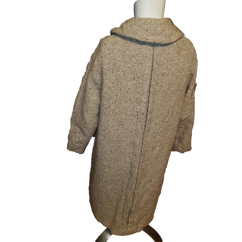 May include: A long, brown tweed coat with a blue trim on the collar. The coat has a single button closure and a straight silhouette.