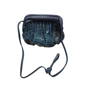 May include: A blue snakeskin-textured crossbody bag with a matching strap. The bag has a gathered design and a rounded shape. The strap is thin and adjustable, allowing the bag to be worn over the shoulder or across the body.