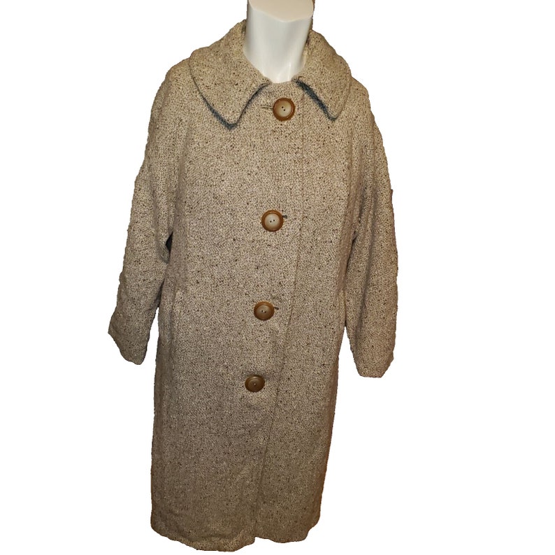 May include: A long, beige tweed coat with a collar and five brown buttons. The coat is on a white background.