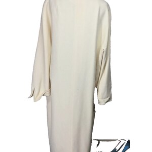 May include: A long, off-white coat with a simple design and long sleeves. The coat is made of a soft, textured fabric.