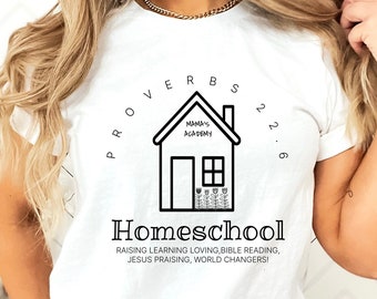 May include: White t-shirt featuring a black and white graphic of a house with the text "Mama's Academy" above it. The graphic is surrounded by a circle with the text "Proverbs 22:6" and the word "Homeschool" below it. The text below the graphic reads "Raising learning loving, bible reading, Jesus praising, world changers!"