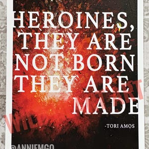 May include: A red, orange, and black abstract art print with white text that reads "Heroines, they are not born they are made - Tori Amos". The print also includes the text "@anniemgo" at the bottom.