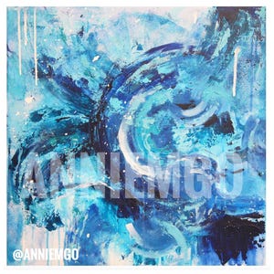 May include: Abstract painting with a swirling design in shades of blue, turquoise, and white. The artwork features visible brushstrokes and paint drips, with the artist's name, "ANNIEMGO," and social media handle, "@ANNIEMGO," overlaid on the image.
