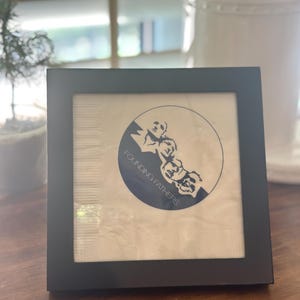 May include: A black framed picture with a white background and a blue circle with the text "Founding Fathers" and a silhouette of three men's faces.