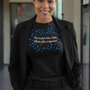 May include: Black t-shirt with a blue star pattern and the text "Put on your shoes, ladies. There's glass everywhere!"