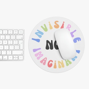 May include: A round mouse mat with a white background and a rainbow coloured circle around the edge. The text "INVISIBLE NO IMAGINATION" is written in black letters inside the circle.