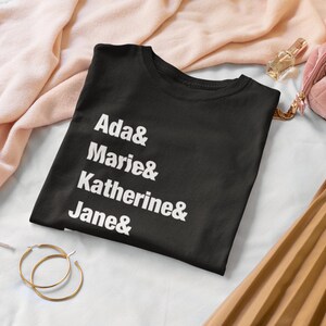 May include: Black t-shirt with white text that reads "Ada & Marie & Katherine & Jane &"