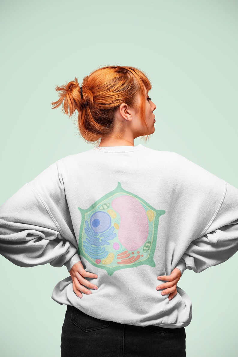 Puede incluir: Una sudadera blanca con una ilustraci&oacute;n verde, azul y rosa de una c&eacute;lula vegetal en la espalda.