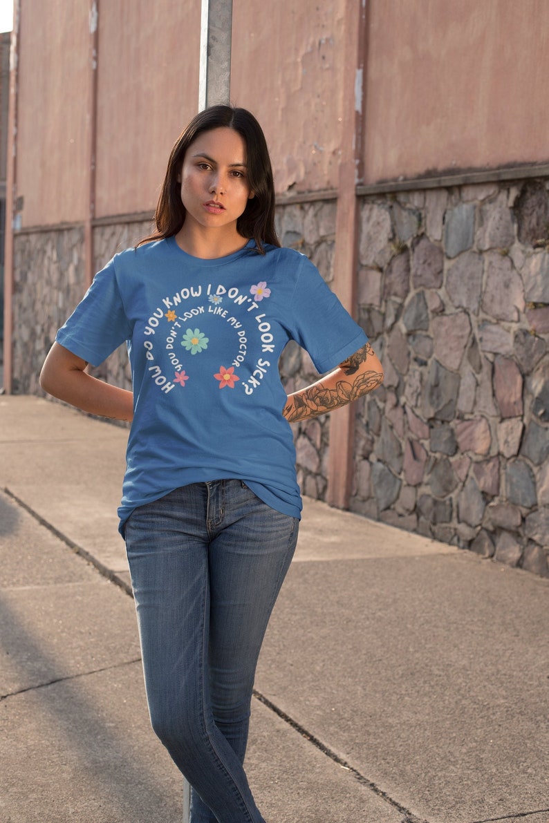May include: A blue t-shirt with a white graphic that says "How do you know I don't look sick?" with flowers around the text.