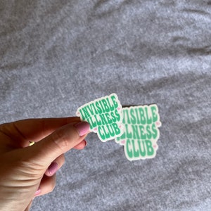 May include: Two green and white stickers with the text "Invisible Illness Club" in a retro font. The stickers have pink hearts around the text.