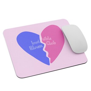 May include: A pink and blue mouse pad with a broken heart design. The left side of the heart is blue and says "Invisible Illness" and the right side is pink and says "Visible Club".
