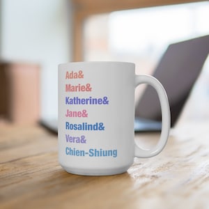 Peut inclure: Une tasse en céramique blanche avec une liste de noms en différentes couleurs : Ada, Marie, Katherine, Jane, Rosalind, Vera et Chien-Shiung.
