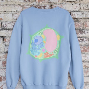 Puede incluir: Una sudadera azul claro con un gr&aacute;fico de una c&eacute;lula vegetal en la espalda. La c&eacute;lula es verde, amarilla, rosa y azul.
