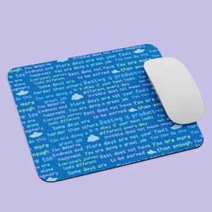 Puede incluir: Alfombrilla de ratón azul con un patrón repetitivo de nubes blancas y texto que dice "Te mereces amabilidad y felicidad. El viaje de cada uno es diferente. Algunos días son más difíciles que otros. Descansar es productivo. Está bien si tu mejor día es diferente cada día. Invisible no significa imaginario. Estás haciendo un gran trabajo. Puedes hacer más de lo que se necesita. No estás solo."