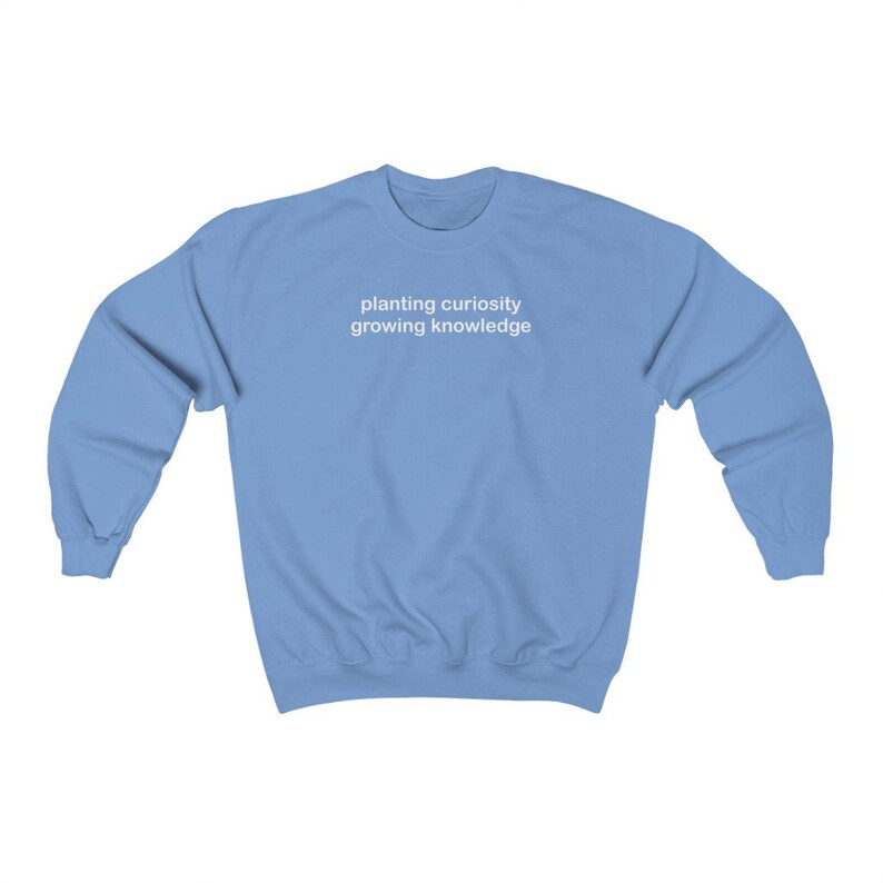 Puede incluir: Una sudadera azul claro con el texto "planting curiosity growing knowledge" impreso en blanco en la parte delantera.