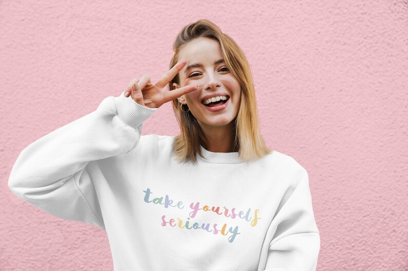 May include: A white sweatshirt with the text "take yourself seriously" in rainbow colors.