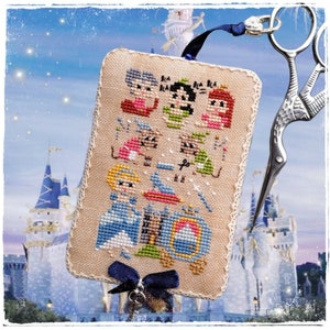Op de afbeelding: Een borduurwerk ornament met een scène uit de Disney film Assepoester. Het ornament is beige met een blauw lint en een zilveren bedel. De scène bevat Assepoester, Prins Charming en de muizen uit de film. De tekst "BLA BLA BLA" is opgenomen in de scène.