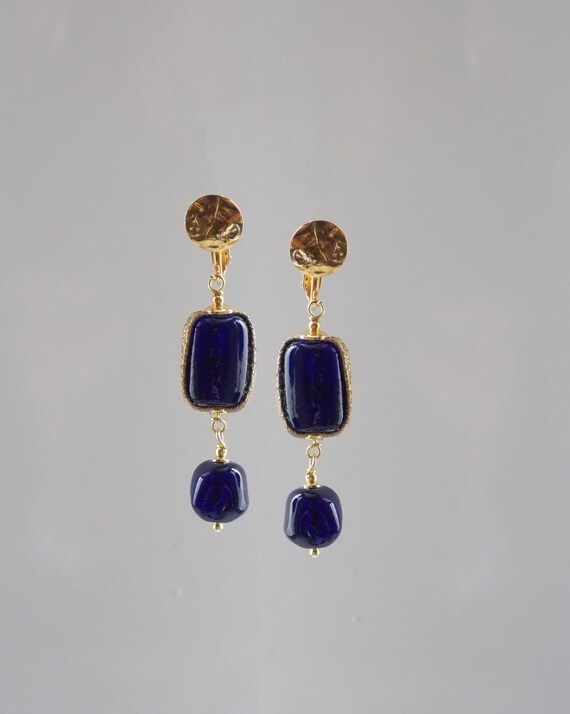 Une paire de boucles d'oreilles pendantes en grosses perles percées