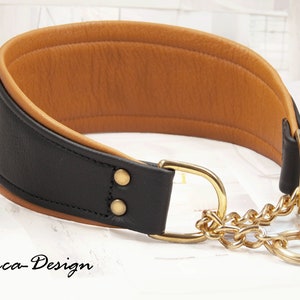 May include: Black leather dog collar with a brown leather lining and a gold chain. The collar has a gold buckle and a gold ring.