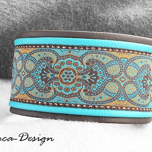 Puede incluir: Una pulsera ancha con base de cuero marrón y una banda turquesa. La banda central presenta un detallado estampado de cachemira en tonos marrón, turquesa y dorado. La pulsera está etiquetada como "Luca-Design".