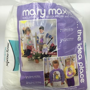 May include: A package of white yarn with a purple and white label featuring a photo of children wearing knitted sweaters with mouse designs. The label reads "mary maxim" and "the idea place".